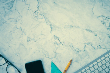 Modern Clean Flat Lay or Top View Office Desk or Office Table and Office Supplies as Computer Keyboard,Pen,Glasses,Smartphone,Triangle Ruler on Marble Minimalist Background in Vintage Tone