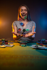 Gambler woman siting at the table in casino and throws chips above the table. Lucky player on smoky...