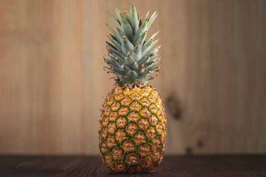 Landscape orientation picture of a Ripe Tropical Pinapple on a wooden table with a wooden background. Tropical fresh healthy fruits 