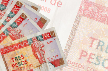 3 cuban pesos convertibles bills lies in stack on background of big semi-transparent banknote....