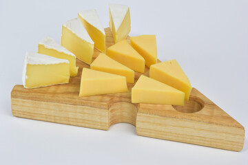 On a special wooden stand for cheese lie several pieces of different types of cheese on a white background