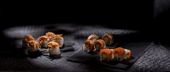 Appetizing rolls on a textured black background. Japanese food concept. Close-up. Copy space.