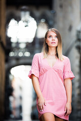 Young romantic woman looking around and walking on old town street