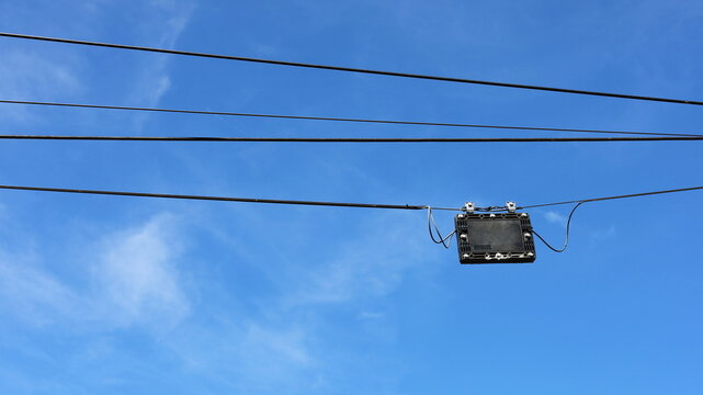 A Black Plastic Box Is Hung On The Wires. Fiber Optic Splitter Box (Plc / Coupler) For Fiber Optic Splitter, High Speed Internet On Blue Background, With Copy Space. Selective Focus