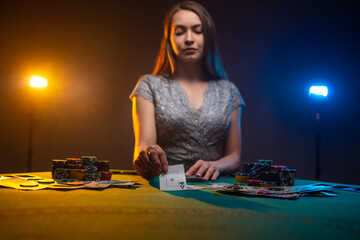 Unemotional woman playing in casino. Lucky player on smoky background with lamps. Concept of poker game.
