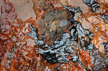 Hazardous waste. Spillage toxic waste in nature. Pollution of the environment. Texture of crude oil spill on the surface of the soil