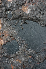 Watter drops on the petroleum surface.Spills of crude oil on the soil surface. Crater of the mud volcano.