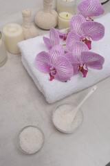 Concept for spa salon,with three  towel and branch pink orchid., ,salt in bowl, stones  on gray background,

