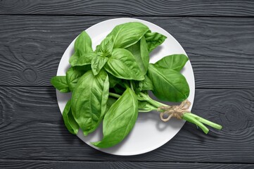Green basil leaves on wooden desk