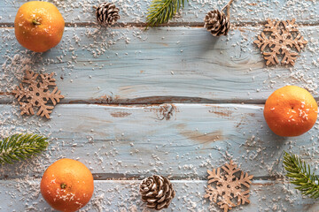 Christmas background. Fresh mandarins, decorative snowflakes, pinecones laid out in the frame on...