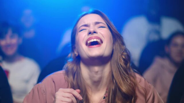 Young woman watching comedy movie in cinema. Happy girl laughing on funny moment