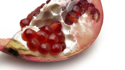 Close up texture of ripe red pomegranate fruit on isolated white background. Detail of pomegranate seeds inside the fruit.