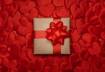 Valentines day. Gift box on decorative red hearts background. Top view, flat lay