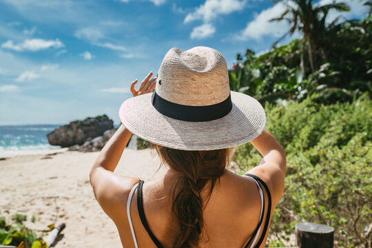 Girl at the sea. Tropical landscape and a girl in a hat photographs the beach