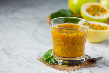 a glass of passion fruit juice place on white marble floor