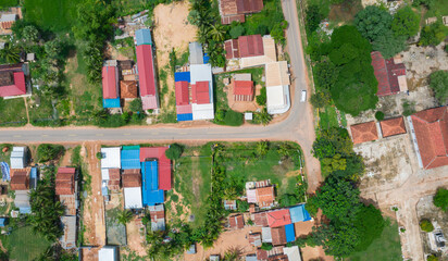 Obraz premium Main dirt road in rural village in Cambodia. There are houses on either side of the road.