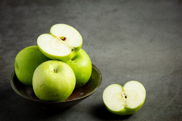 fresh green apples cut in half put in black bowl on dark background
