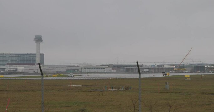 Luggage and security cars in the runway of Arlanda airport on rainy day