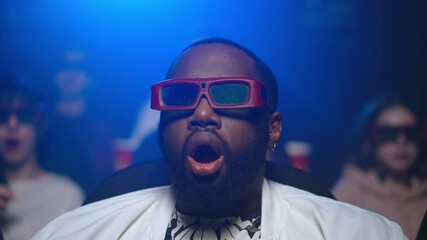 Afro man feeling shocked in movie house. African guy eating popcorn at 3d cinema