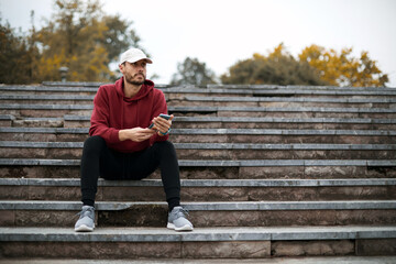 Athletic sporty man training in hoodie sweatshirt in urban city park.