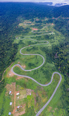 Winding road from the high mountain pass in Cambodia - Thailand  Great road trip trough the dense woods. Aerial view.