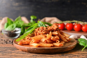 Plate of penne pasta with tomato sauce on wooden background