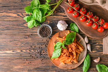 Plate of penne pasta with tomato sauce on wooden background