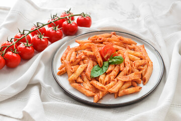 Plate of penne pasta with tomato sauce on light background