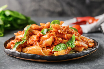 Plate of penne pasta with tomato sauce on dark background