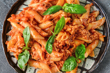Plate of penne pasta with tomato sauce on dark background