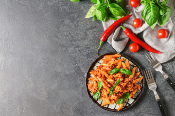 Plate of penne pasta with tomato sauce on dark background
