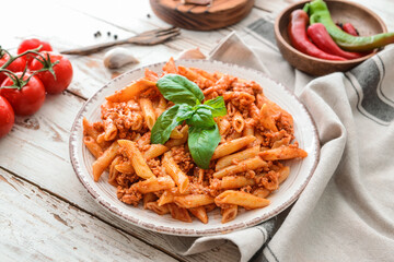 Plate of penne pasta with tomato sauce on wooden table