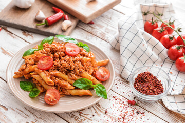 Plate of penne pasta with tomato sauce on wooden background