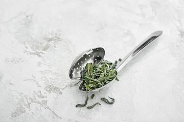 Strainer with dry green tea on light table