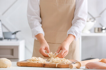 Woman making raw pasta in kitchen