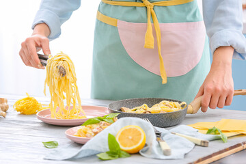 Woman putting pasta on plate in kitchen