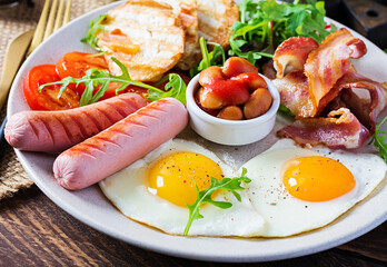 English breakfast - fried egg, beans, tomatoes, sausage, bacon and toast.