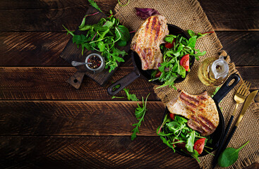 Juicy grilled pork steak with herbs on bone on wooden background. Top view, overhead, flat lay