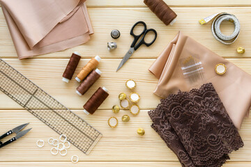 Flat lay of sewing accessories. Cloth, threads and tailoring tools on wooden background