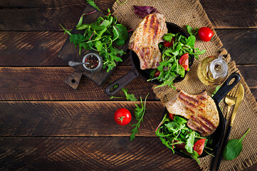 Juicy grilled pork steak with herbs on bone on wooden background. Top view, overhead, flat lay