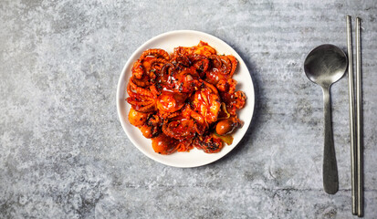Fried squid with spicy Korean sauce on gray concrete table.