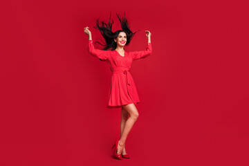 Full length body size view of adorable cheerful model posing having fun wind blow hairstyle isolated on vivid red color background