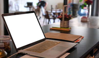 Close - up shot of Mockup laptop blank screen on a cafe table.