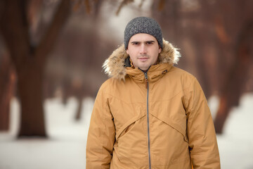 Winter portrait of a man in hat. Christmas time. Snowdrift, cold. Happy new year. Winter holidays in the forest with snow