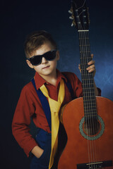 studio portrait of a boy in a stylish image with a classic guitar