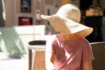 Beautiful Stylish woman wear beach hat to protect her face from UV sunlight damage while enjoy her vacation in the resort. Ultraviolet rays over exposure. Dark spot, Aging skin problem and skin care. - obrazy, fototapety, plakaty