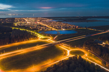 Fototapeta premium Modern sustainable residential neighbourhood in the city of Almere, The Netherlands, Amsterdam suburb, with solar panels farm powering city heating. Evening traffic on the roads. Aerial shot at dusk.