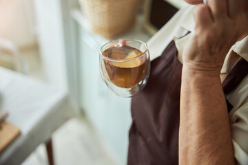 Elderly woman holding cup of tea and talking on cellphone