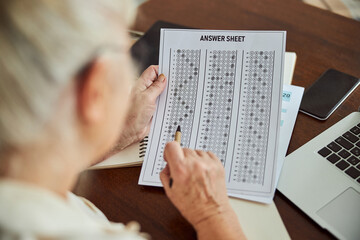 Fototapeta na wymiar Senior woman checking answers for test at home