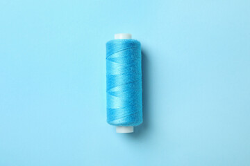 Blue sewing thread on blue background, space for text